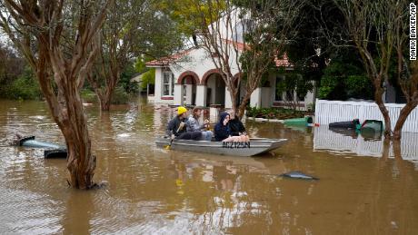 Menschen paddeln am 5. Juli 2022 auf einer überfluteten Straße in Windsor, Australien
