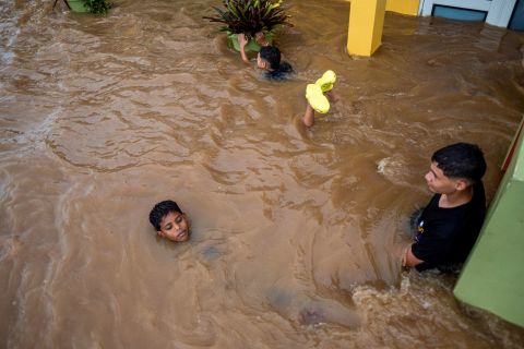 Kinder schwimmen am Montag in einer überfluteten Straße in Salinas.