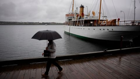 Ein Fußgänger schützt sich mit einem Regenschirm, während er bei Regen entlang der Küste von Halifax spazieren geht, bevor der Hurrikan Fiona am Freitag, den 23. September 2022, in Halifax landet.