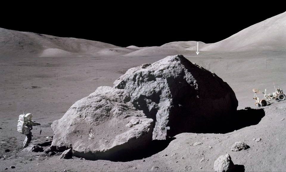 Die Oberflächenzeit von Apollo 17, dem langlebigsten Programm auf dem Mond, betrug drei Tage, zwei Stunden und neunundfünfzig Minuten.  Das Bild zeigt Jack Schmidt von der Raumsonde Apollo 17, der einen Skorpion zurück zur Mondlandefähre trägt, nachdem er die Ostseite eines massiven Felsbrockens beobachtet und beprobt hat.  Der vertikale Pfeil in der Ferne zeigt auf die Mondlandefähre Challenger, die sich etwa 3,1 km entfernt befindet.