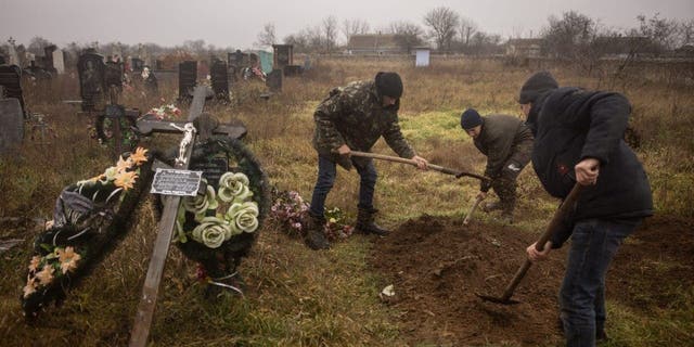 Ukrainische Einwohner und Beamte exhumieren die Leiche eines 16-jährigen Mädchens und sieben weiterer Männer, die von russischen Streitkräften getötet und am 29. November 2022 in der Stadt Pravdin am Stadtrand von Cherson begraben wurden.