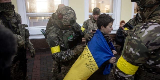 Ein Junge hält seine ukrainische Nationalflagge, die von Angehörigen des ukrainischen Militärs am 19. November 2022 in Cherson, Ukraine, unterzeichnet wurde.